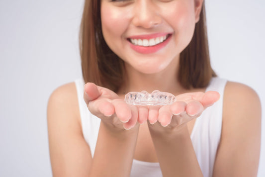 Smiling woman holding clear dental aligners in hands
