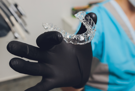 Clear aligner tray held by dental professional during online consultation process.
