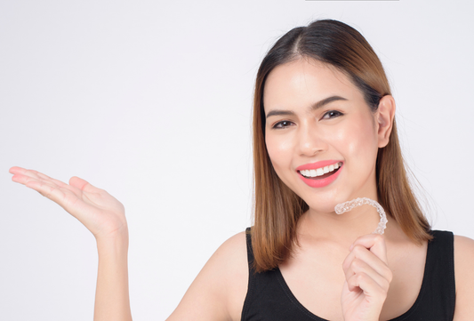 Smiling woman holding clear aligners in her hand before starting teeth straightening treatment while travelling in Europe.